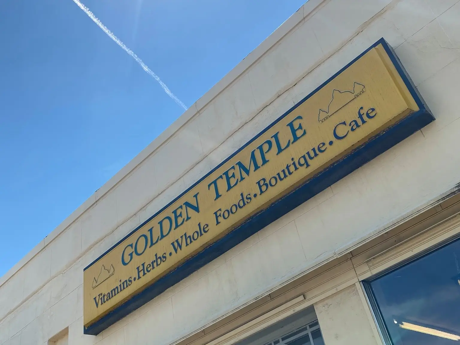 The Golden Temple flagship location store sign shot from below with a blue sky behind it